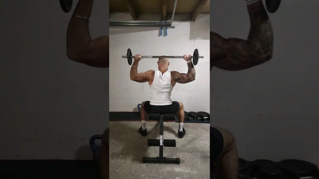 Développé nuque assis barre (seated barbell behind the neck shoulder press)