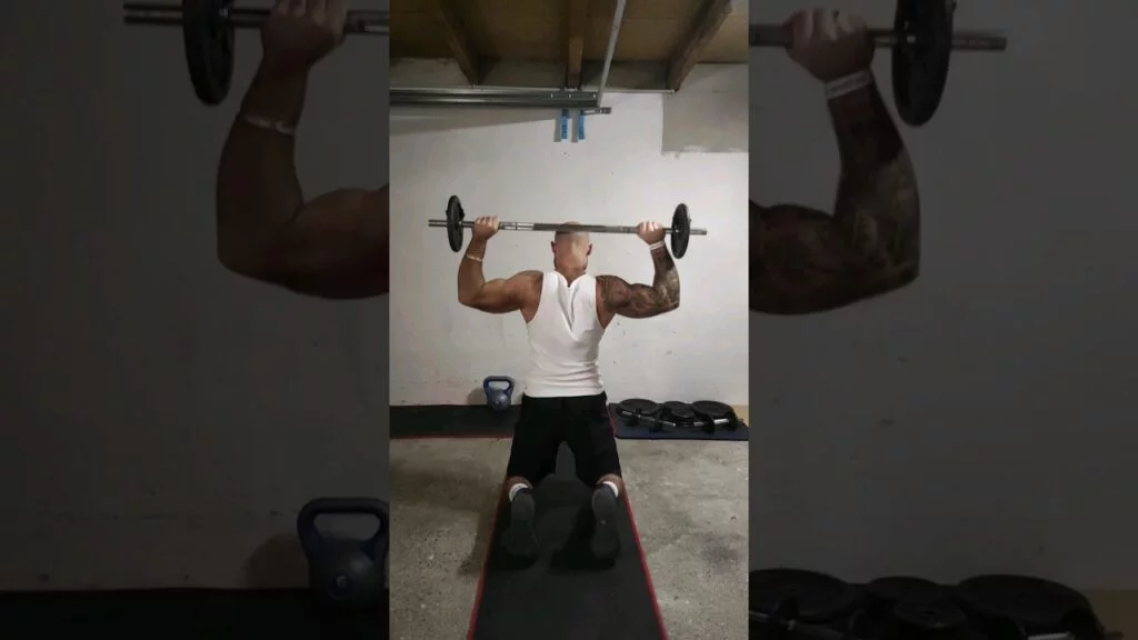 Développé nuque à genou barre (kneeling barbell behind the neck shoulder press)